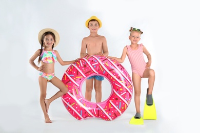 Cute little children in beachwear with bright inflatable ring on white background