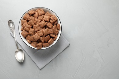 Photo of Sweet crispy corn pads in bowl and spoon on light table, flat lay. Space for text