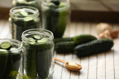 Glass jars with fresh cucumbers and other ingredients on table, closeup. Space for text