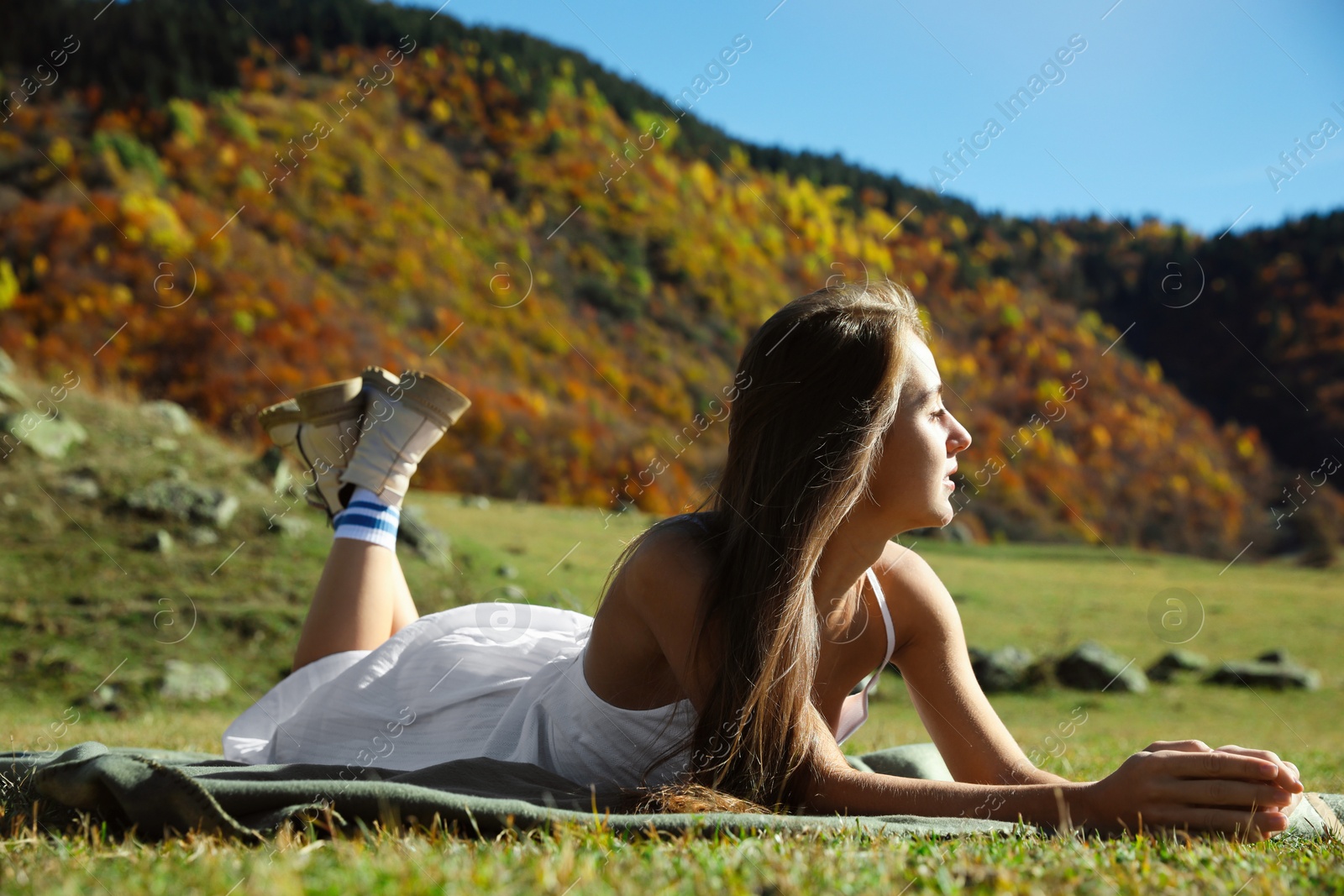 Photo of Beautiful young woman relaxing on blanket in mountains