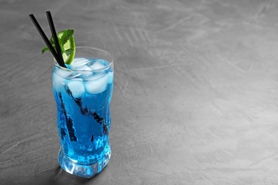 Photo of Glass of tasty refreshing cocktail with mint and lime on grey table. Space for text