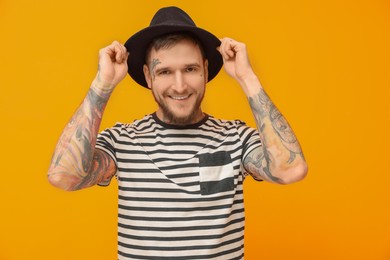 Photo of Portraithandsome hipster man wearing stylish hat on orange background