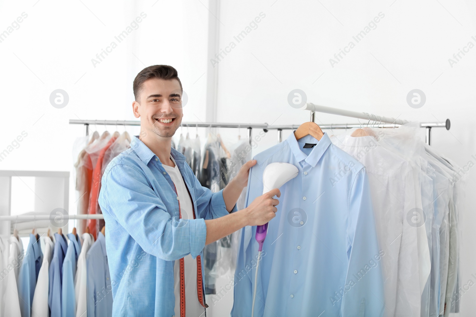 Photo of Young man steaming shirt at dry-cleaner's