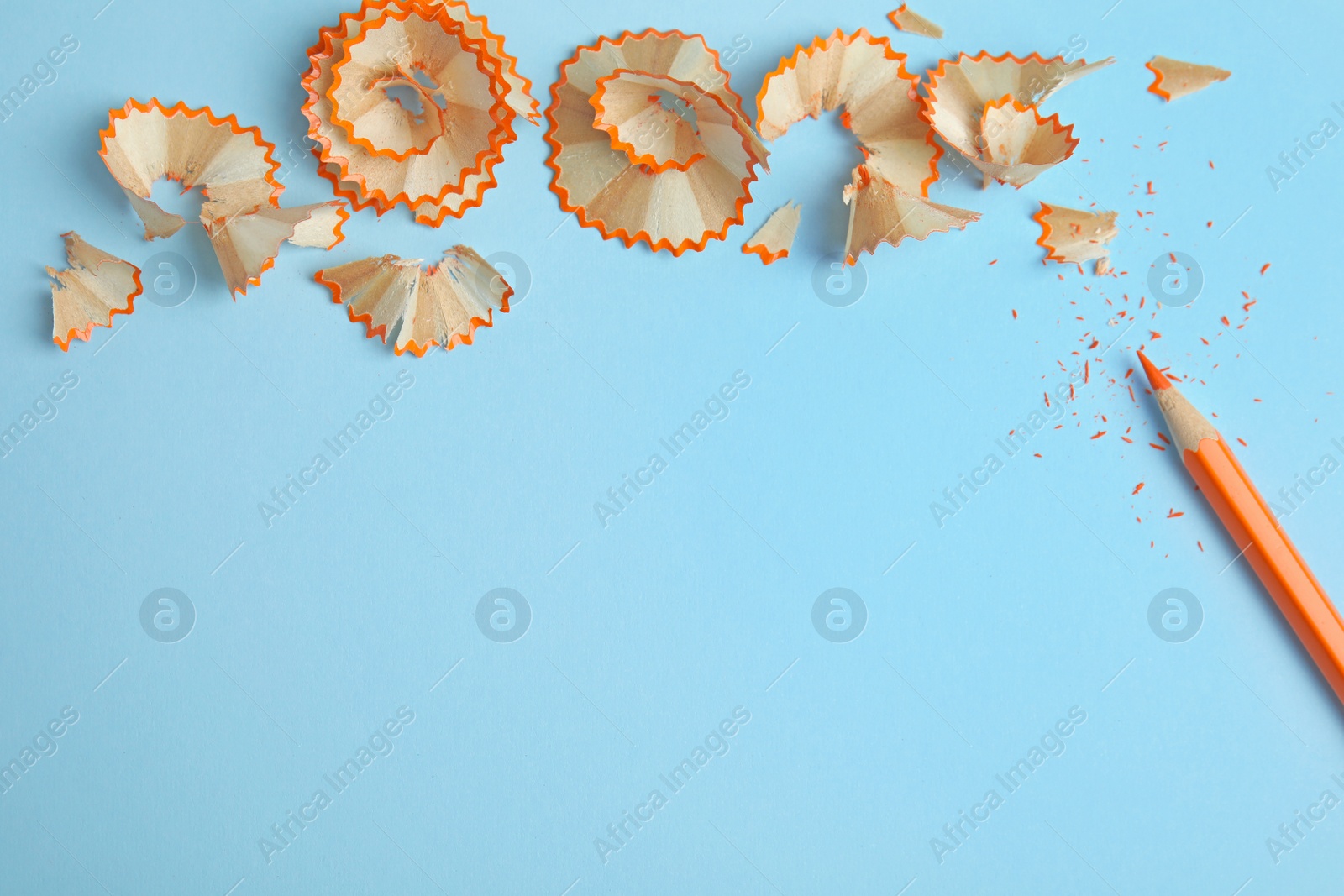 Photo of Color pencil and shavings on blue background, flat lay. Space for text
