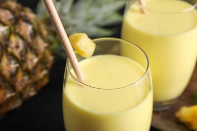 Photo of Tasty pineapple smoothie and fruit on table, closeup