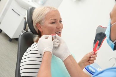Photo of Professional dentist showing patient teeth cover in clinic