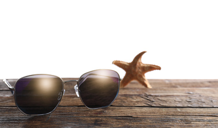 Photo of Stylish sunglasses and starfish on wooden table against white background. Space for text
