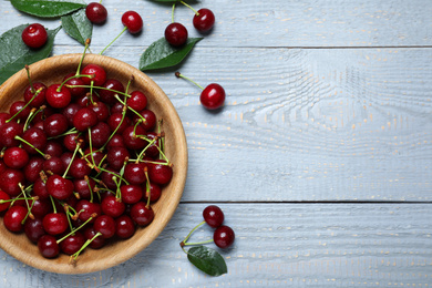 Photo of Sweet juicy cherries on blue wooden table, flat lay. Space for text