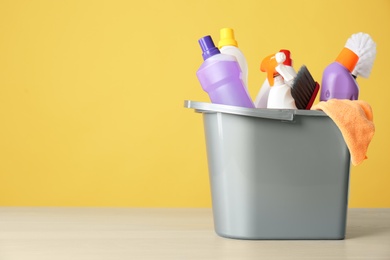 Photo of Bucket with cleaning products and tools on grey table. Space for text