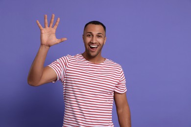 Man giving high five on purple background. Space for text
