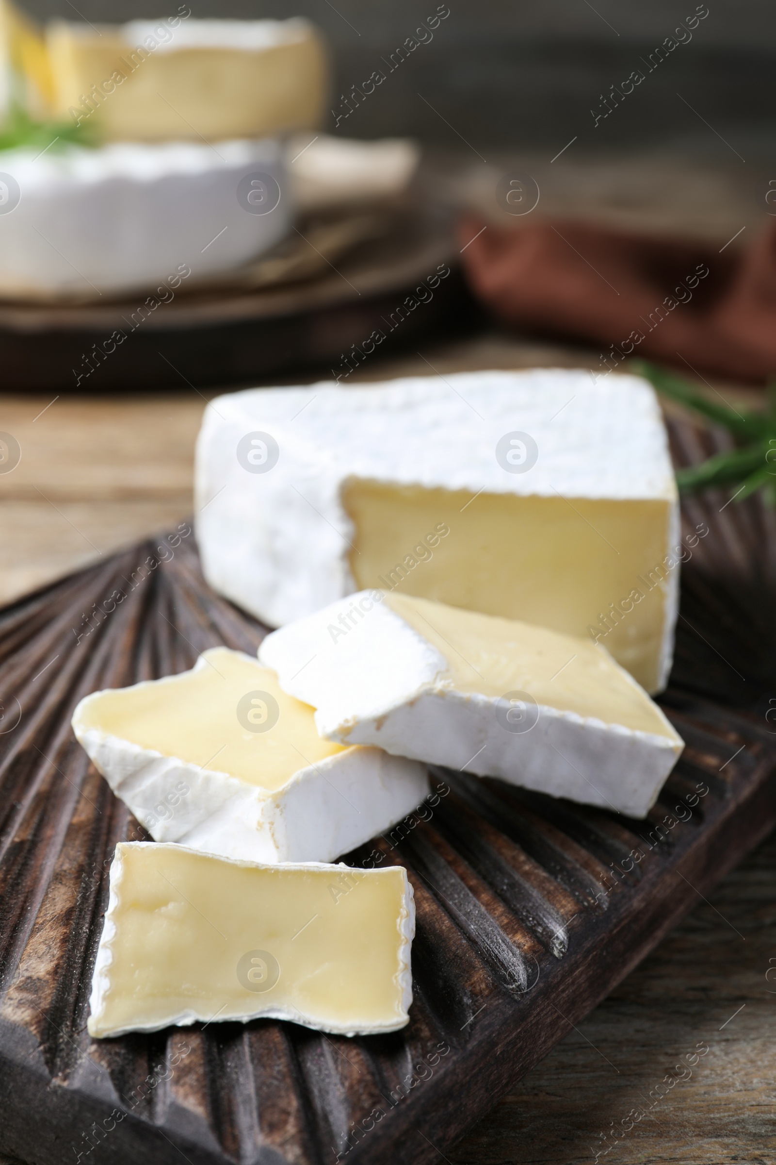 Photo of Tasty cut brie cheese on wooden board, closeup