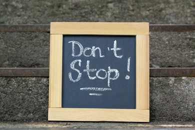 Photo of Chalkboard with phrase Don't Stop on stone stairs outdoors