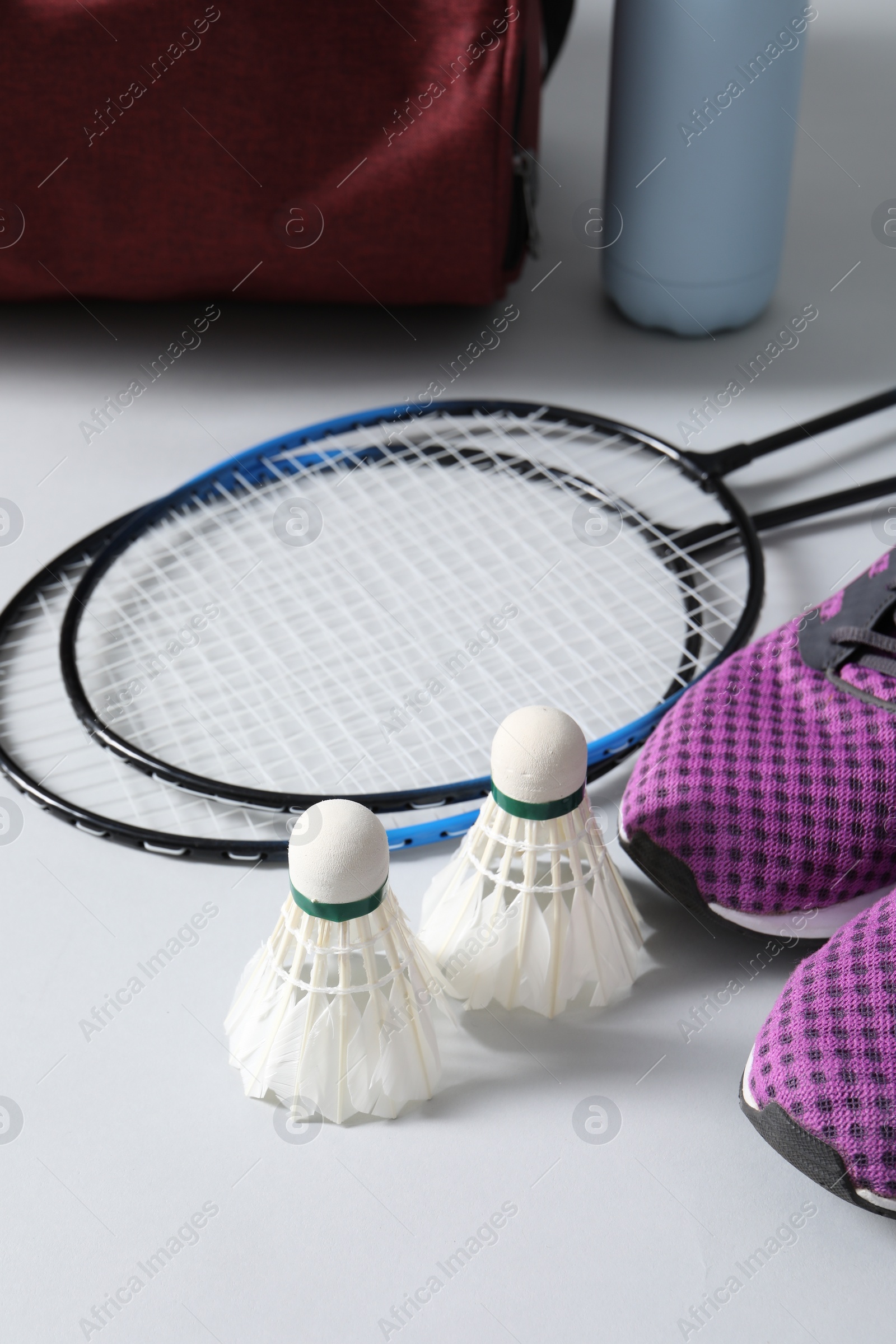 Photo of Feather badminton shuttlecocks, rackets and sneakers on gray background