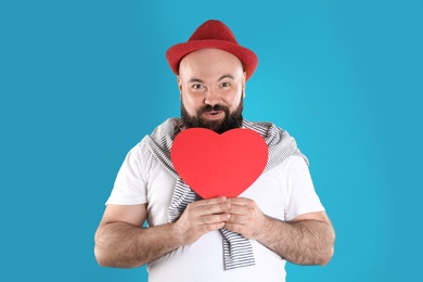 Photo of Emotional man with paper heart on color background
