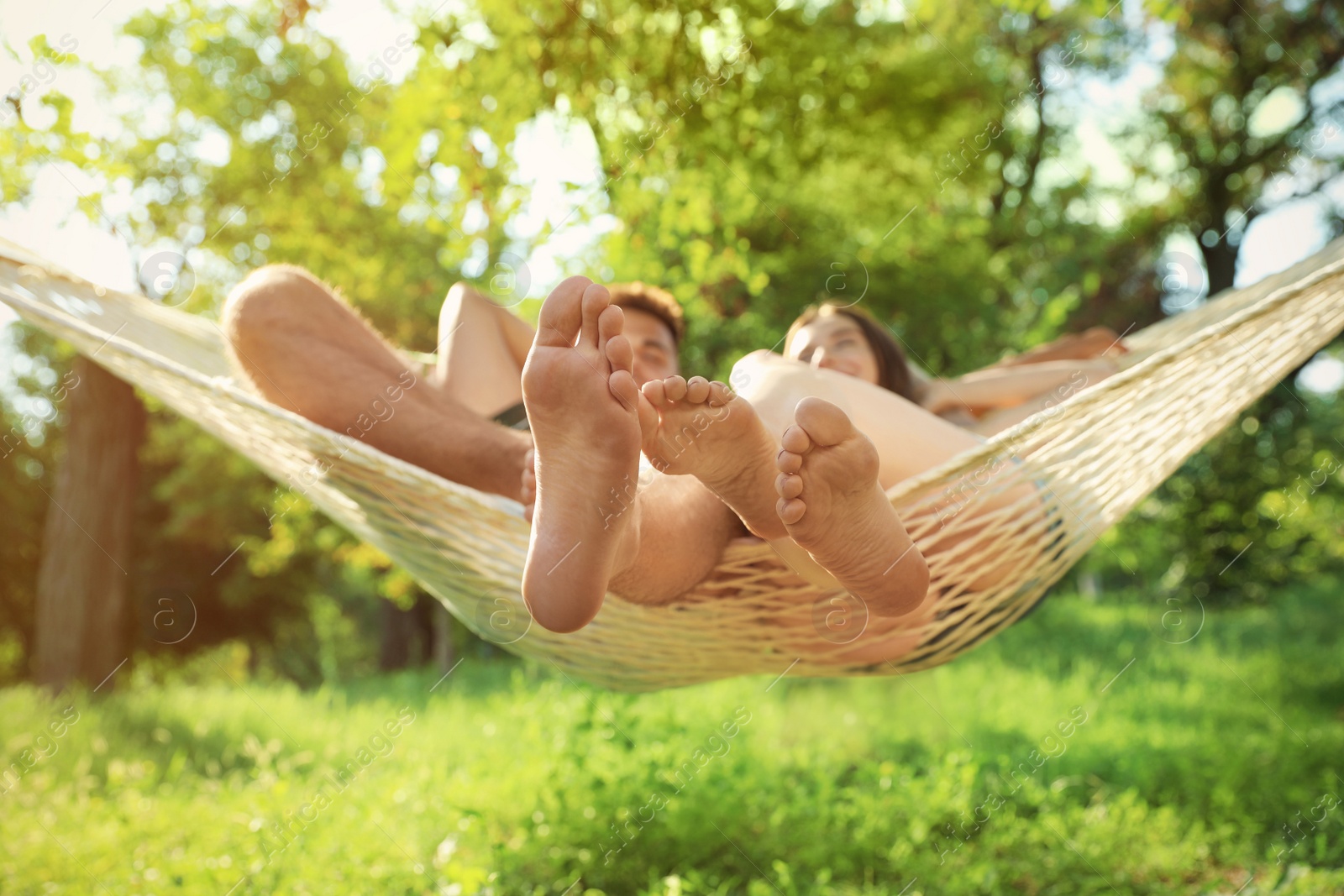 Photo of Young couple resting in comfortable hammock at green garden