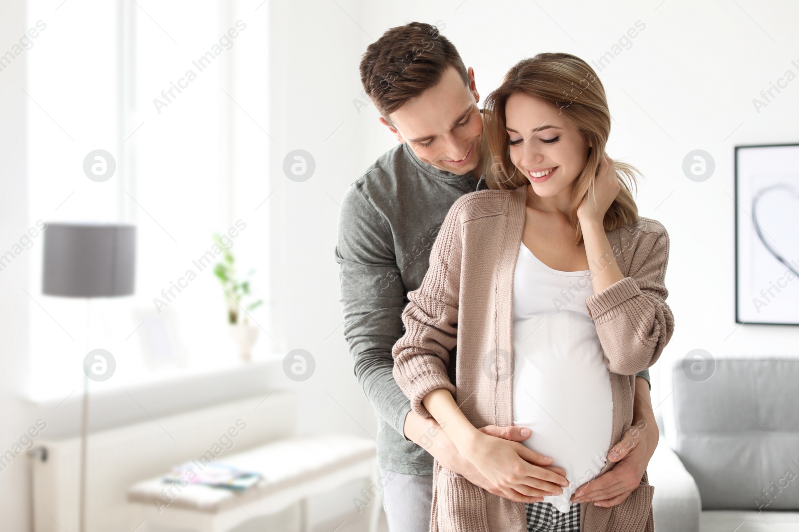 Photo of Young pregnant woman with her husband at home