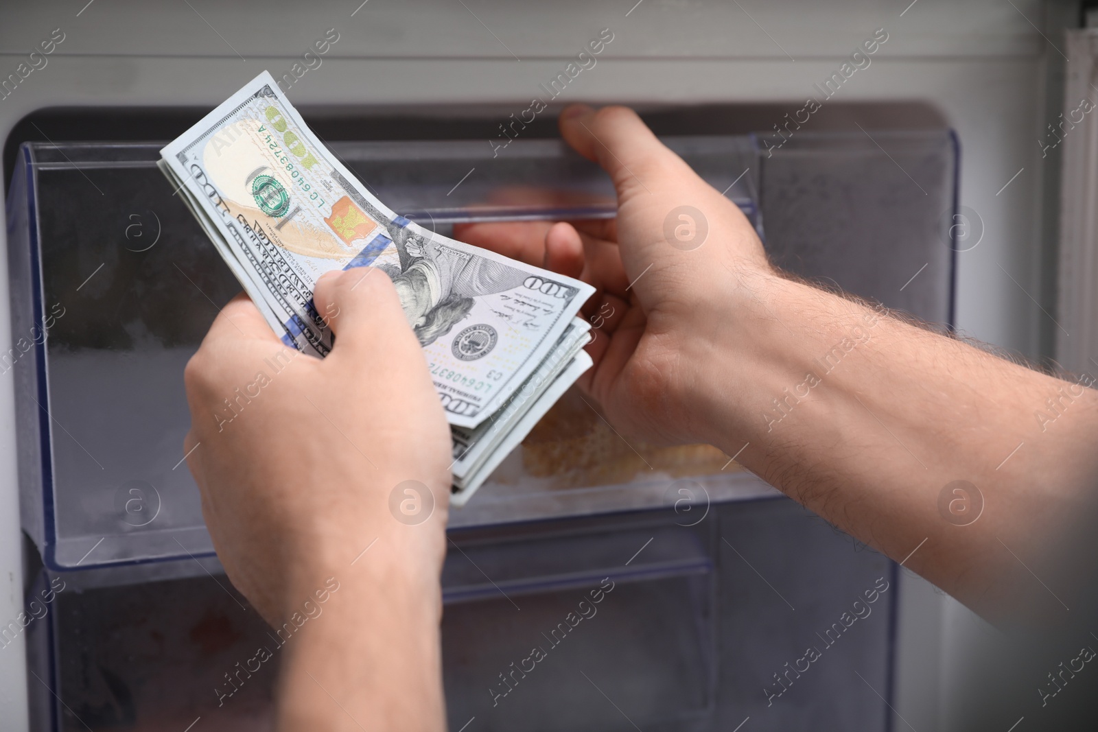 Photo of Man hiding money in refrigerator, closeup. Financial savings