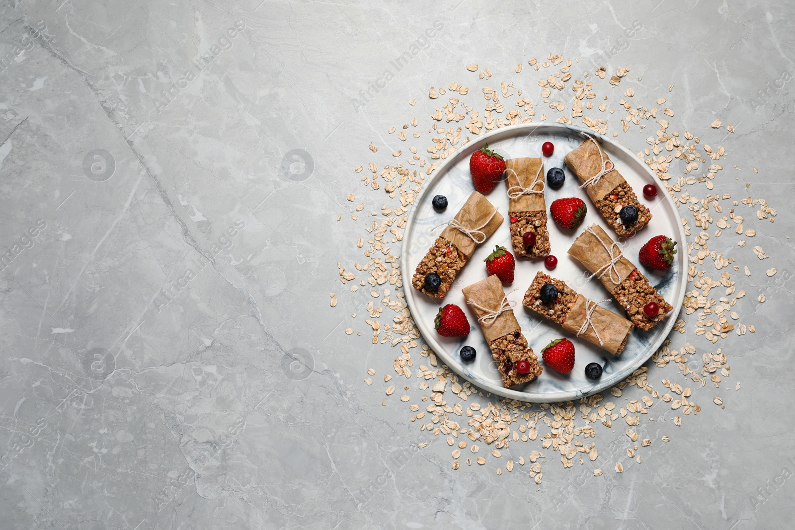 Photo of Tasty granola bars and ingredients on light grey table, top view. Space for text