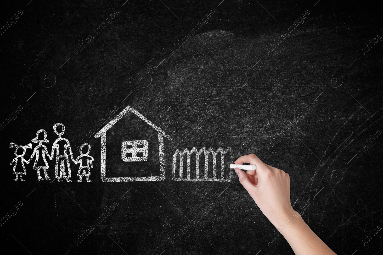 Image of Woman drawing house and family on chalkboard, closeup