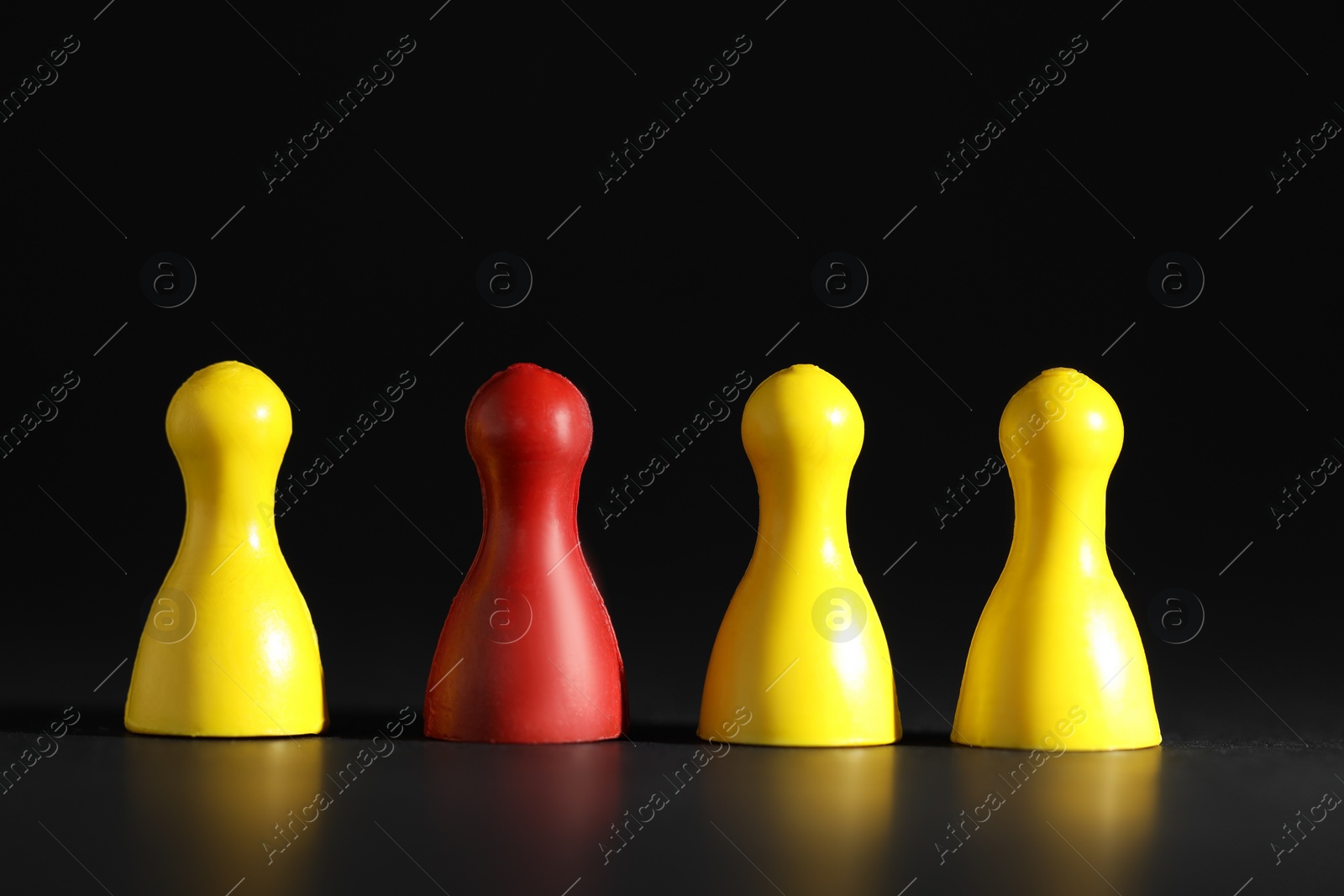 Photo of Choice concept. Red pawn among yellow ones on black table, closeup