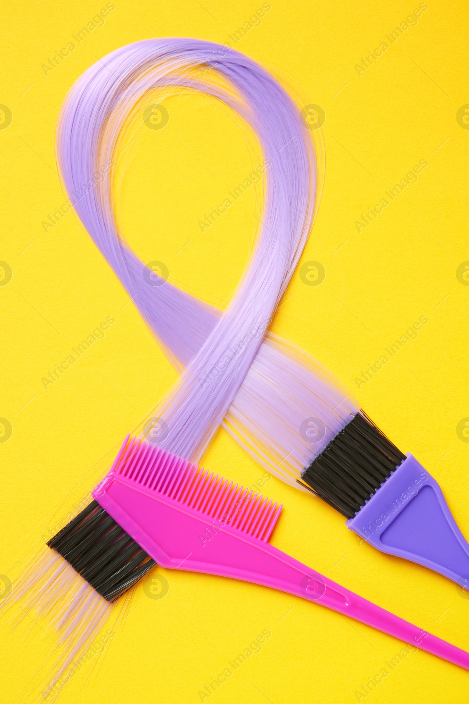 Photo of Flat lay composition with strand of hair and brushes on color background