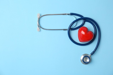 Stethoscope and heart model on color background, top view. Medical equipment