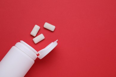 Photo of Jar with chewing gums on red background, flat lay. Space for text