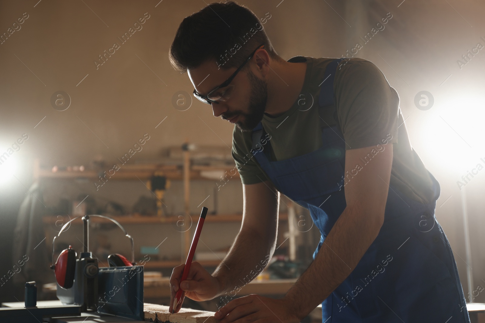 Photo of Professional carpenter making mark on wooden board in workshop