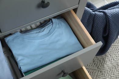 Photo of Sorting and organizing. Chest of drawers with different folded clothes indoors, above view