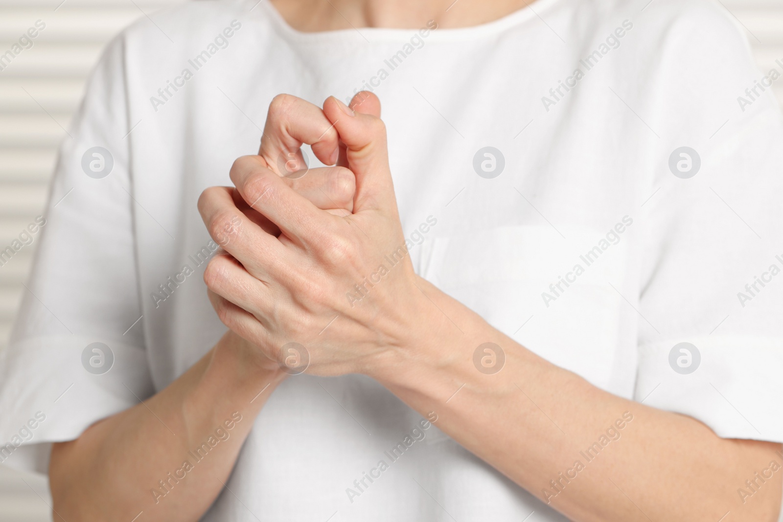 Photo of Woman cracking her knuckles on blurred background, closeup. Bad habit