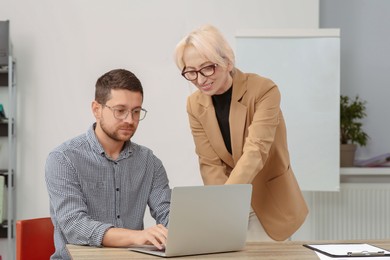 Photo of Boss and employee with laptop discussing work issues in office