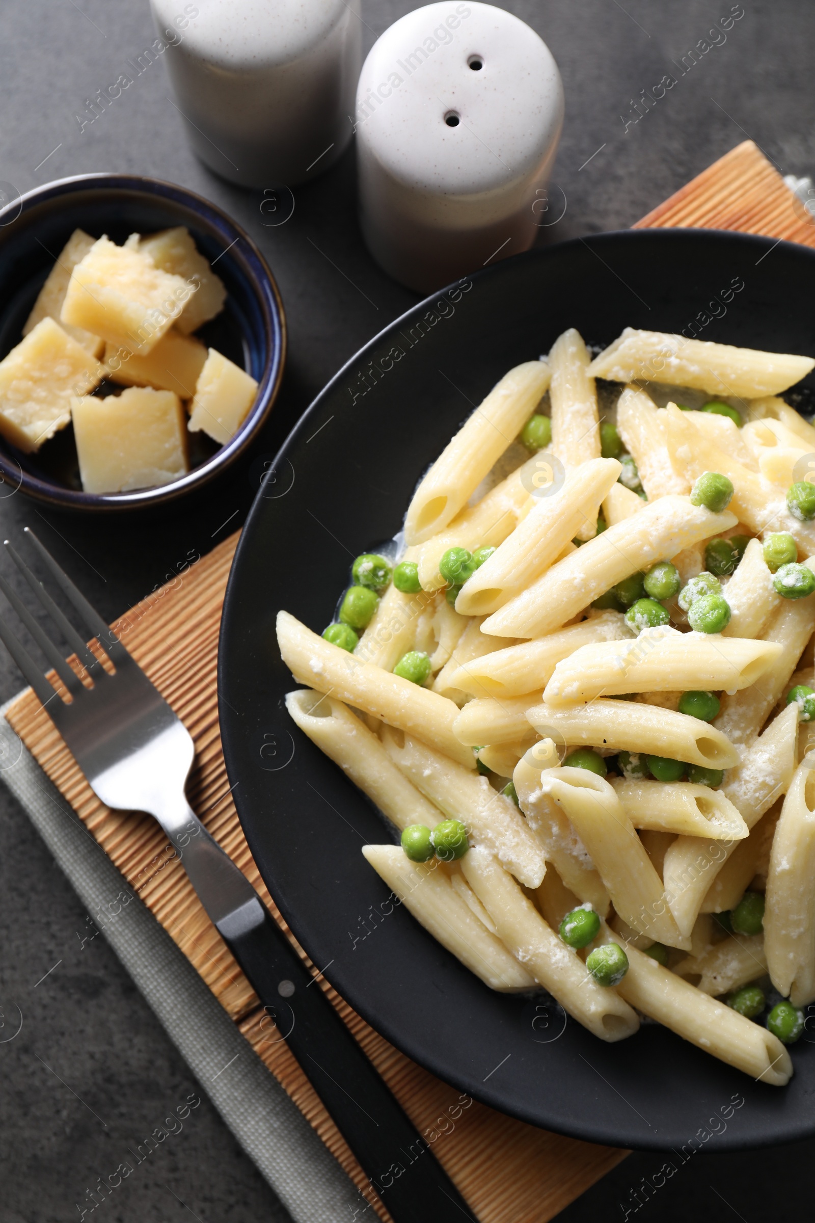 Photo of Delicious pasta with green peas, cheese and fork on grey table, top view