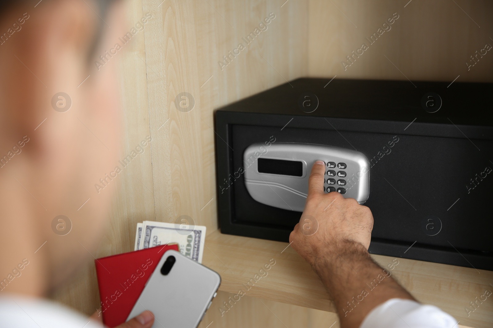 Photo of Man opening black steel safe with electronic lock at hotel, closeup