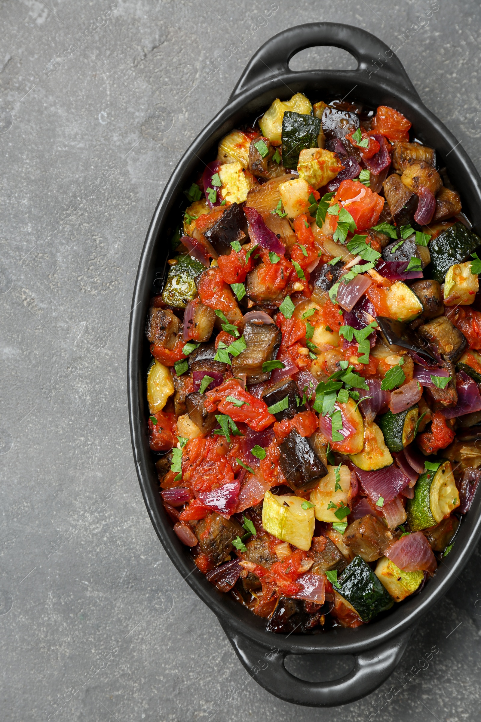 Photo of Dish with tasty ratatouille on grey textured table, top view