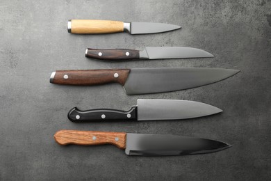 Many different knives on grey textured table, flat lay