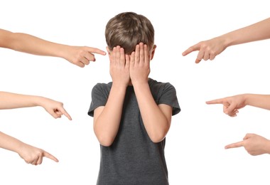 Boy covering face with hands and kids pointing at him on white background. Children's bullying