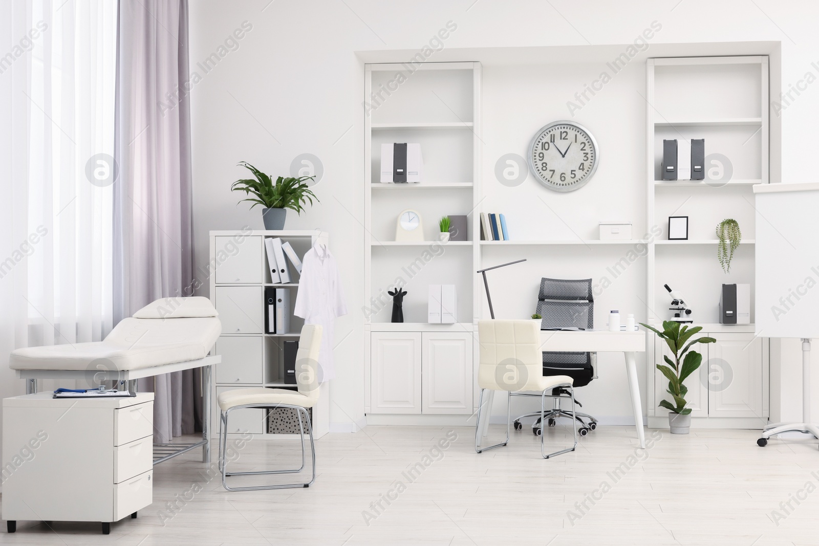 Photo of Modern medical office interior with doctor's workplace and examination table