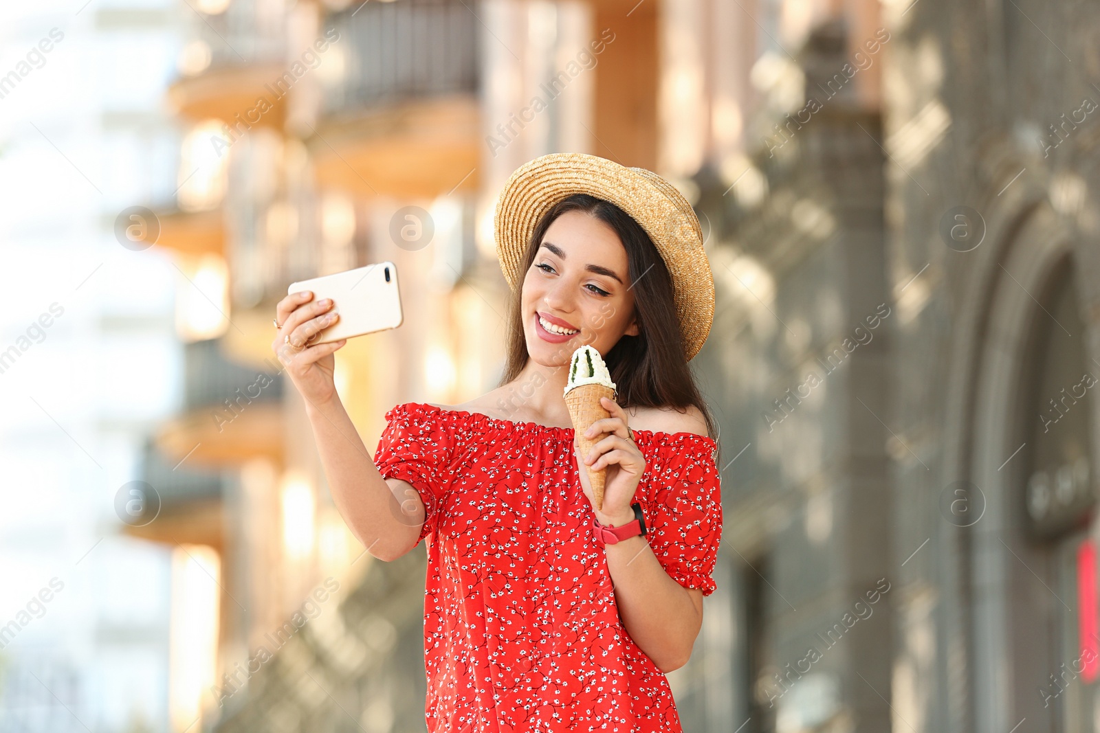 Photo of Happy young woman with delicious ice cream in waffle cone taking selfie outdoors