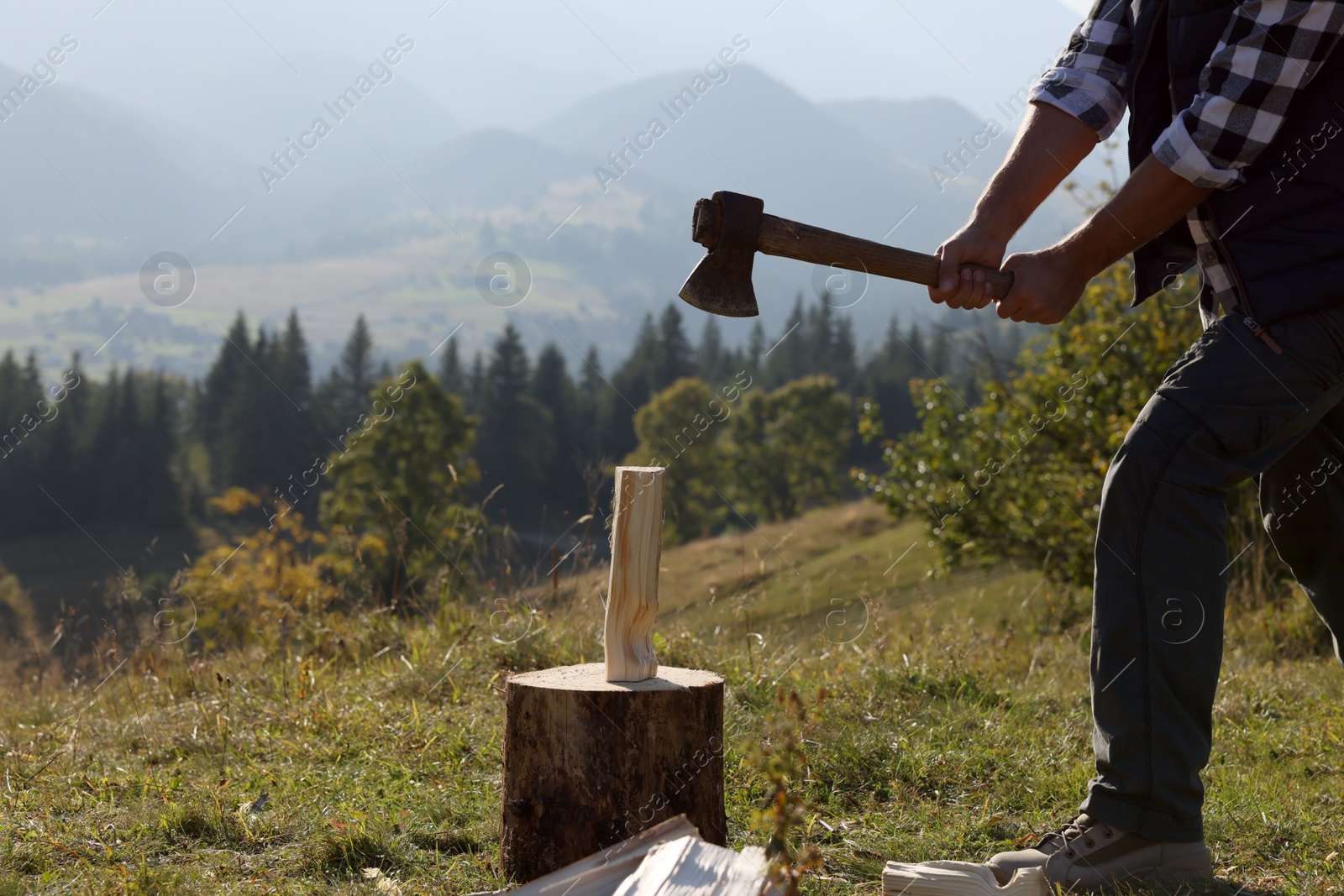 Photo of Man with axe cutting firewood on hill, closeup