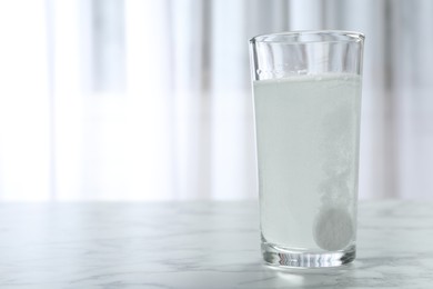 Photo of Glass of water with effervescent tablet on marble table indoors, space for text