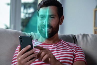 Image of Man using smartphone with facial recognition system at home. Security application scanning his face for approving owner's identity