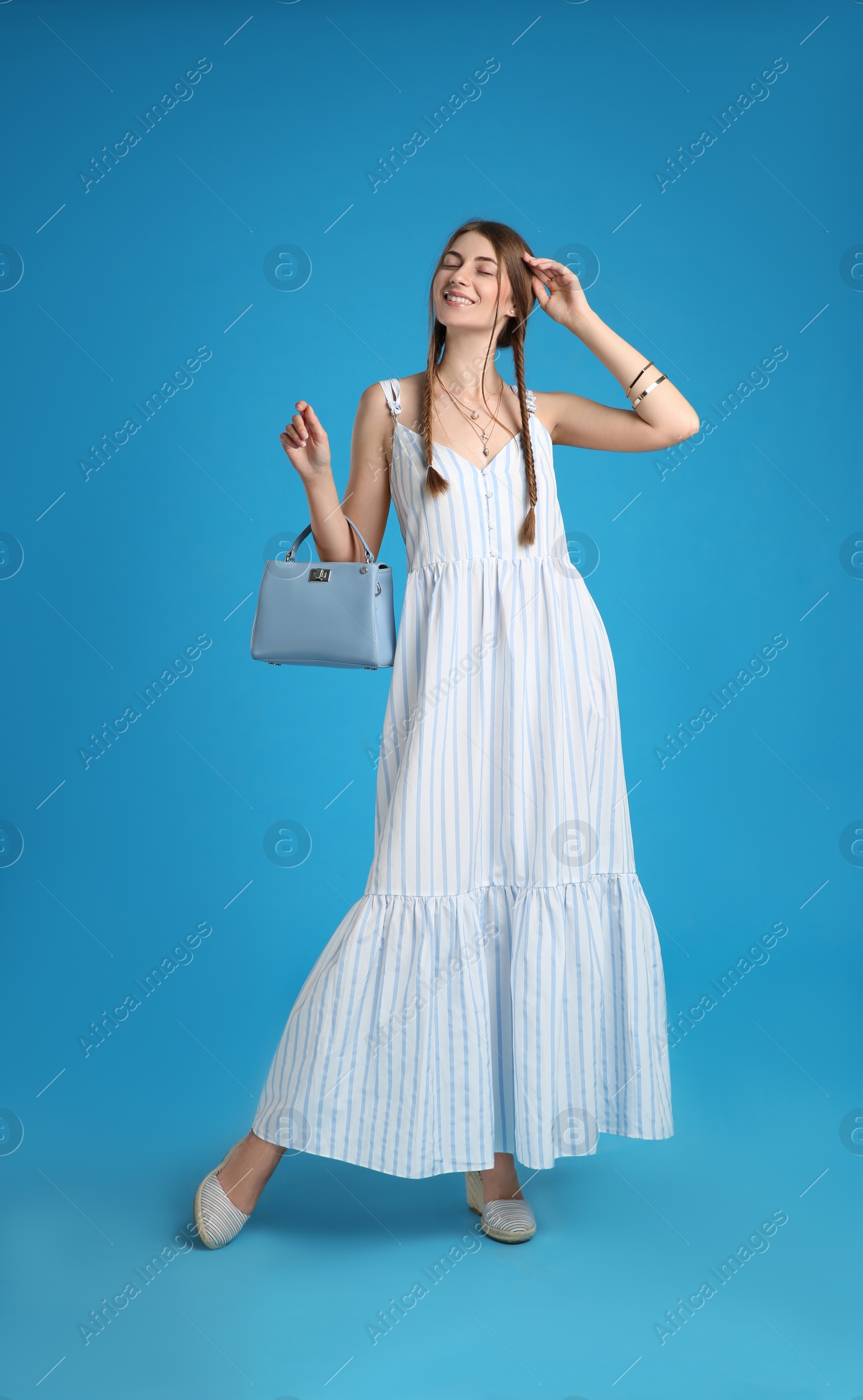 Photo of Beautiful young woman with stylish bag on light blue background