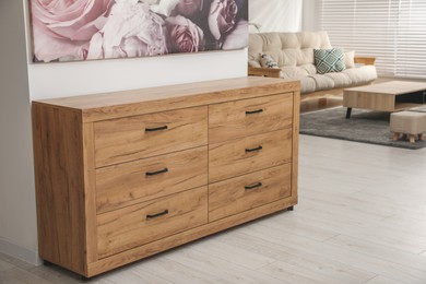 Wooden chest of drawers near white wall in stylish room