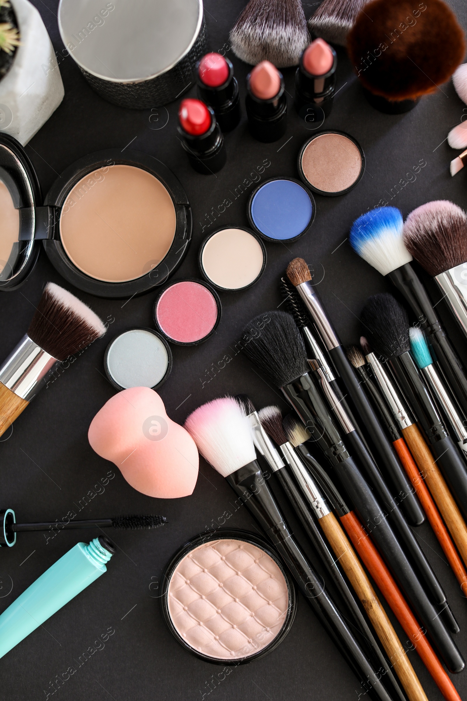 Photo of Flat lay composition with makeup brushes and cosmetic products on black background