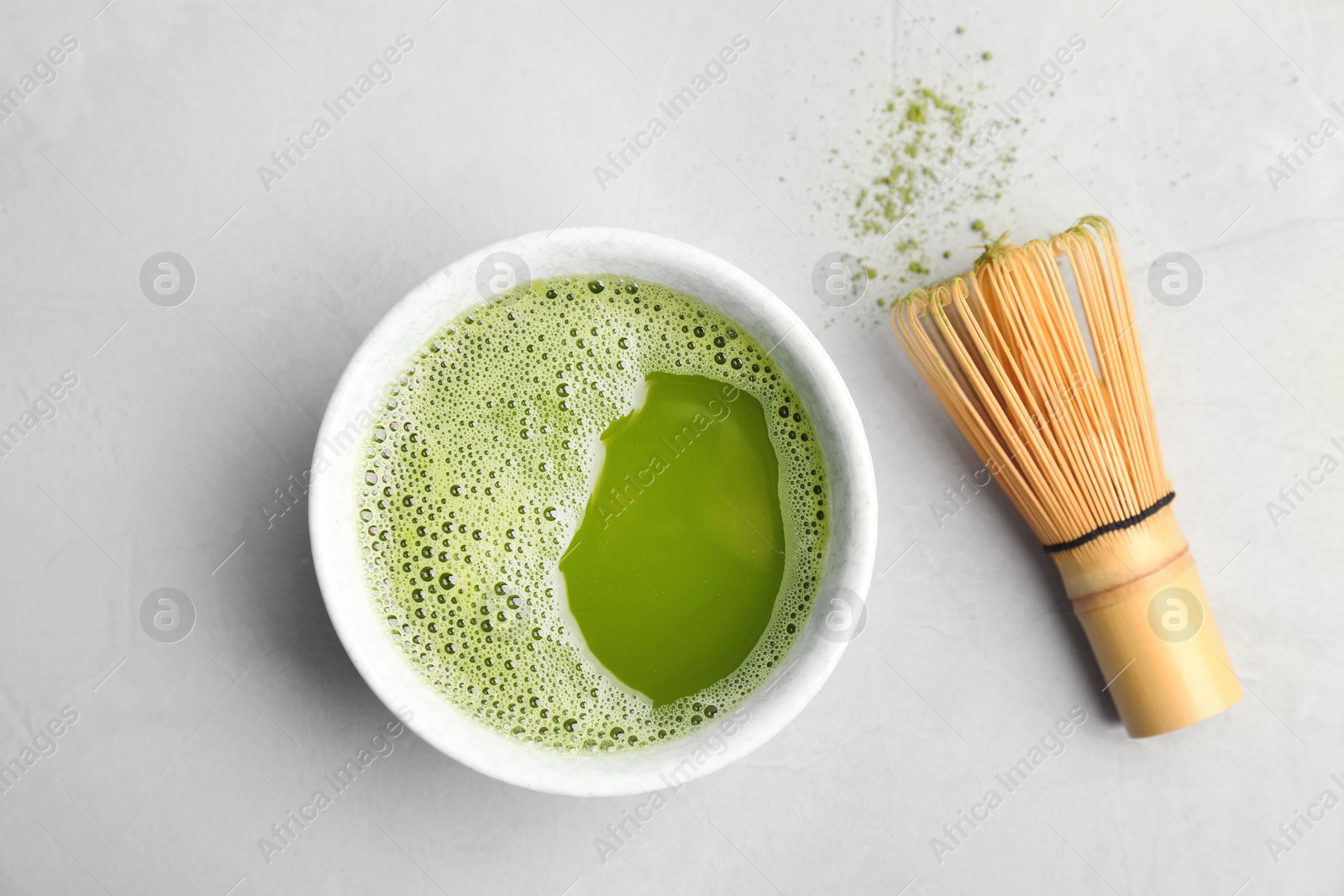 Photo of Chawan with fresh matcha tea and chasen on grey background, top view
