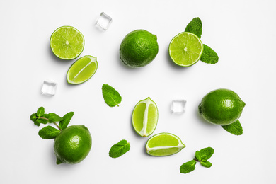 Flat lay composition with fresh juicy limes, mint and ice cubes on white background