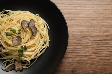 Photo of Tasty spaghetti with truffle on wooden table, top view. Space for text