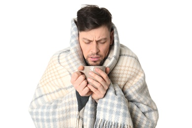 Man with cup of hot tea suffering from cold on white background