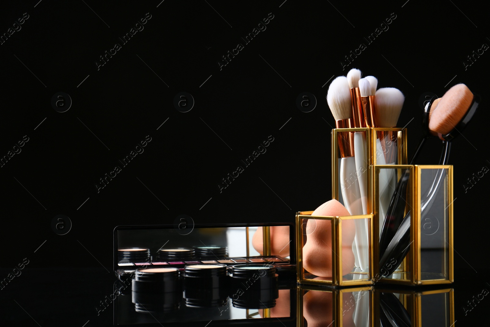 Photo of Set of makeup products and brushes on dark background. Space for text