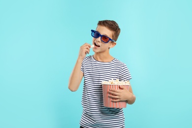 Photo of Boy with 3D glasses and popcorn during cinema show on color background